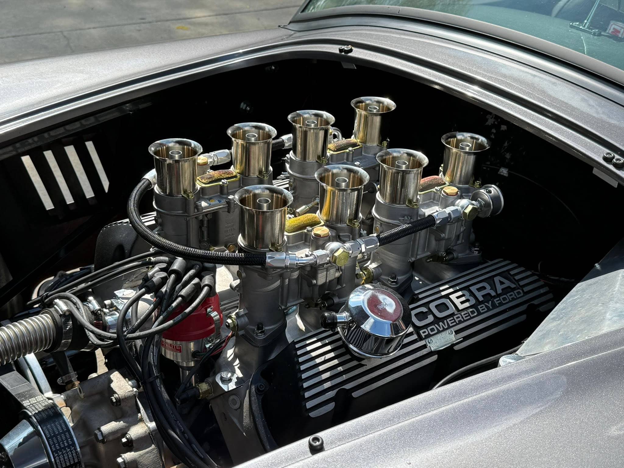 Ford Cobra engine with eight polished intake stacks and black Cobra Powered by Ford valve covers.